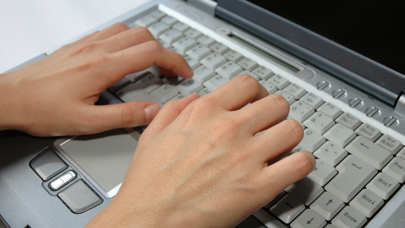 En person med fingrarna över tangentbordet på en laptop.